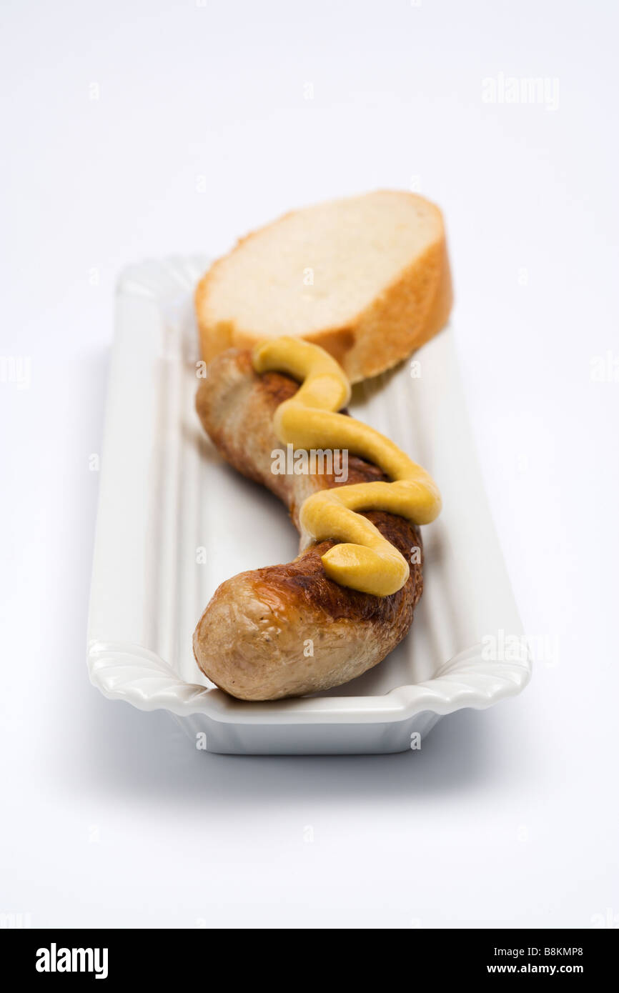 Deutsche Thüringer Bratwurst mit Senf und Brot auf Teller, platziert auf weißem Hintergrund, Frontalansicht Stockfoto