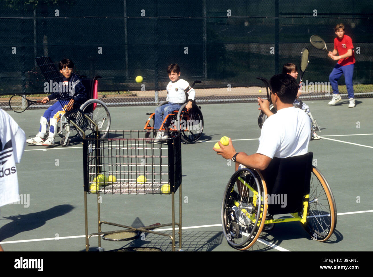 Coach im Rollstuhl unterrichtet Studenten im Rollstuhl Tennis spielen Stockfoto