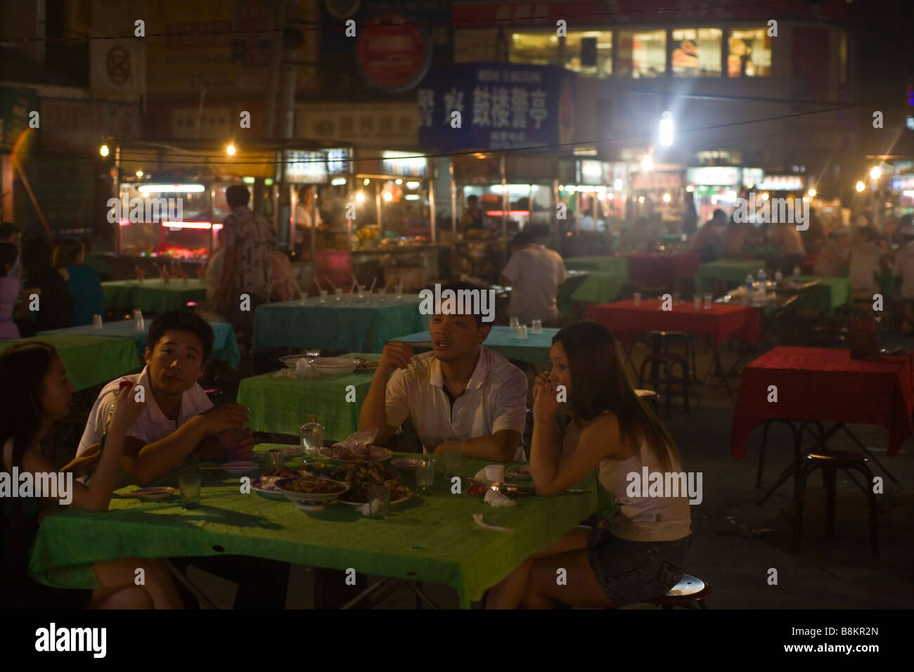 Junge Einheimische genießen ein Mitternacht-Dinner auf dem Nachtmarkt von Kaifeng, Henan Provinz, China. Stockfoto