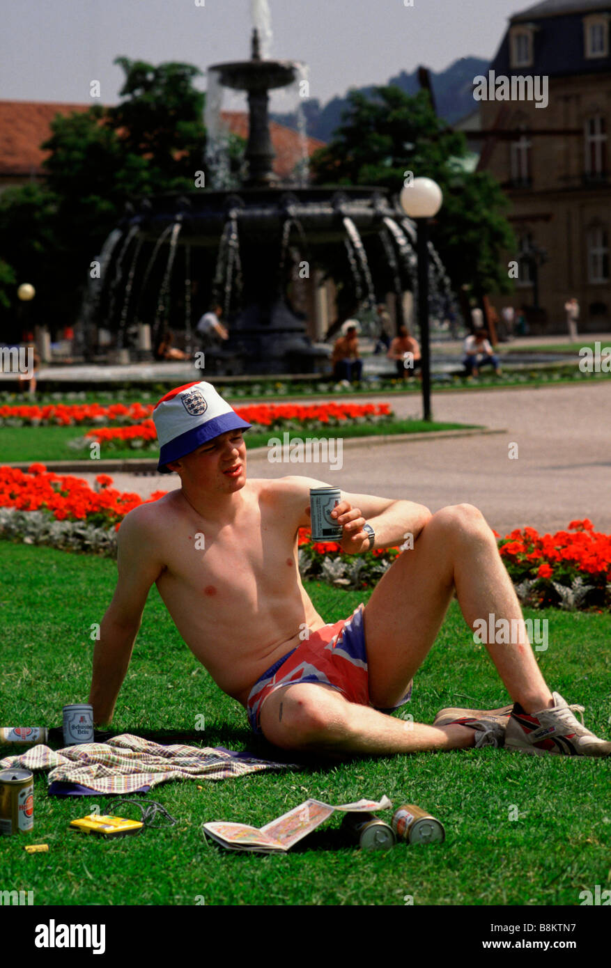 Bundesrepublik Deutschland sitzt eine britische Fußball-Fan in kurzen Hosen Union Jack auf einem Flecken des Grases ein Bier trinken Stockfoto