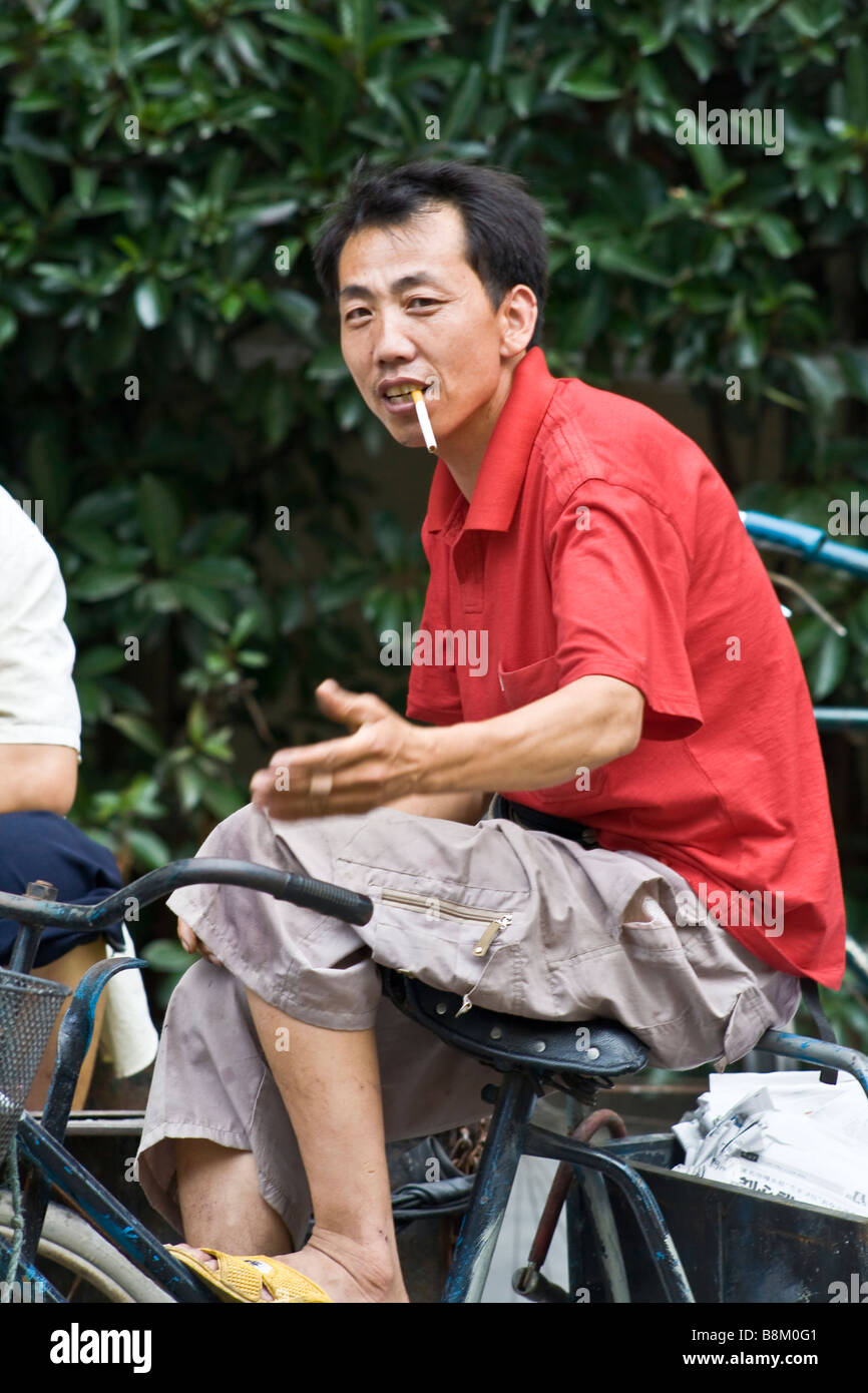 Chinesischen Zigarette Raucher auf einem Fahrrad in Shanghai, China. Stockfoto