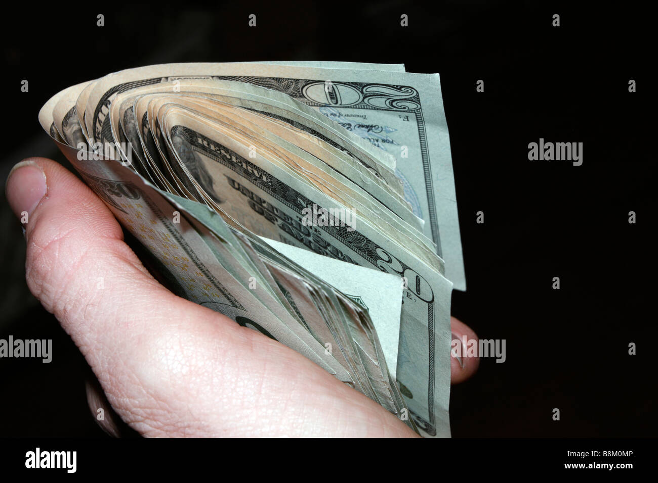 Hand mit losen Stapel von gefalteten USA zwanzig-Dollar-Scheine auf schwarz. Stockfoto