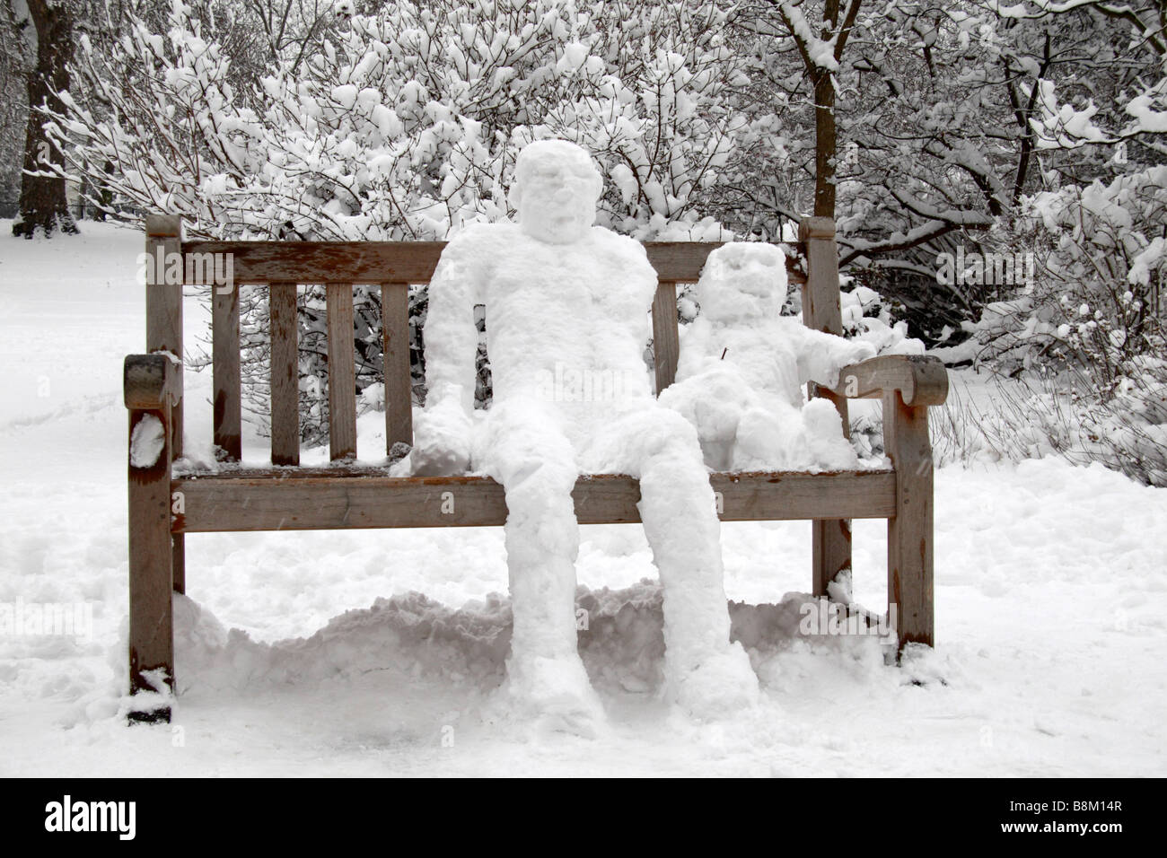 Ein Schneemann und Schnee Kind sitzt auf einer Bank im St James Park, London, während des Schneesturms des 2. Februar 2009. Stockfoto