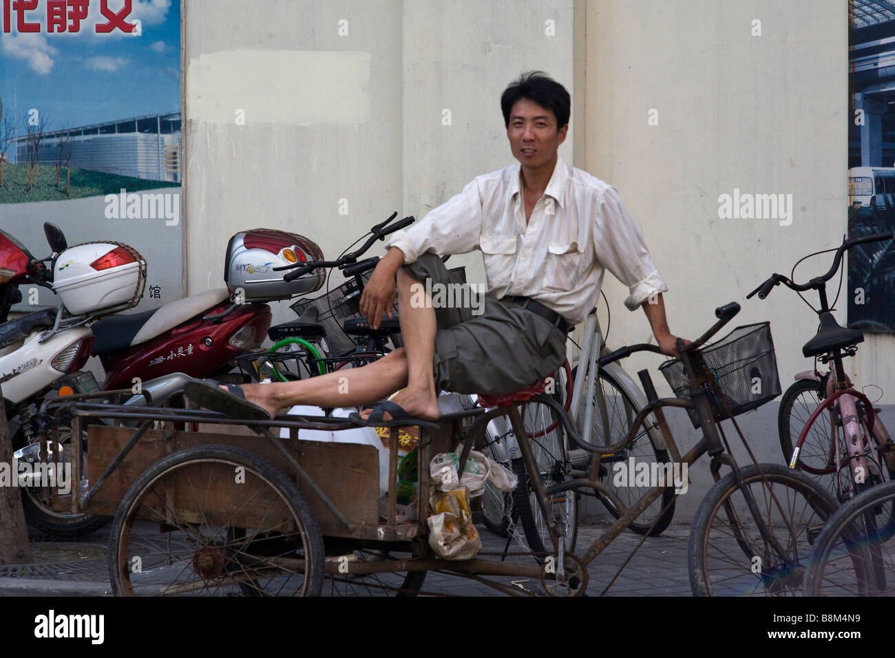 Ein Shanghai Auslieferers ruht auf seinem Dreirad-Wagen. Stockfoto
