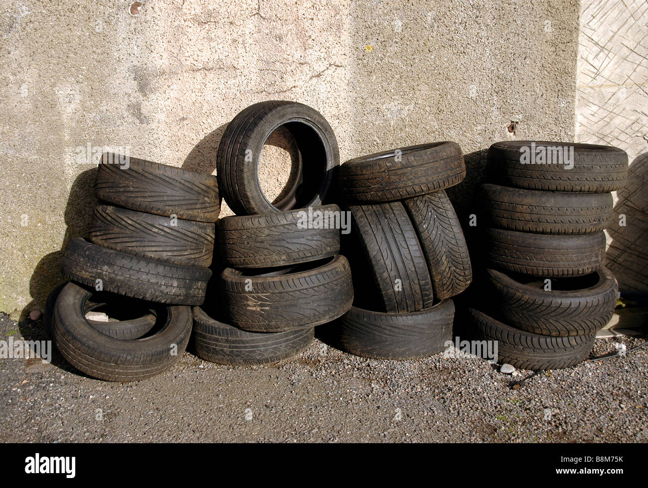 Reifen gestapelt gegen eine Garagenwand. Stockfoto
