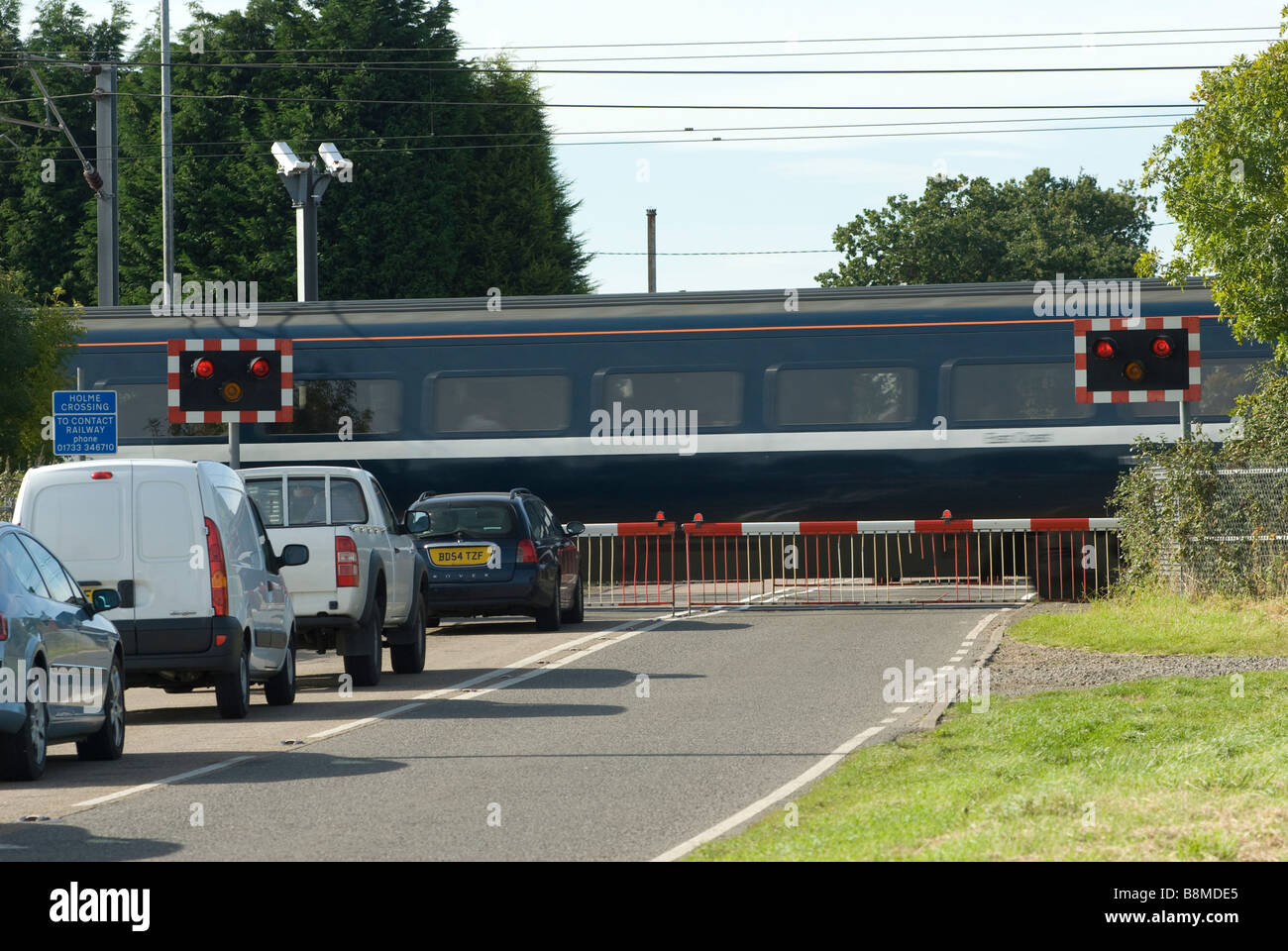 Verkehr an einem Bahnübergang warten, wenn ein Zug auf der Ost-Mantel-Hauptstrecke im Vereinigten Königreich durchläuft Stockfoto