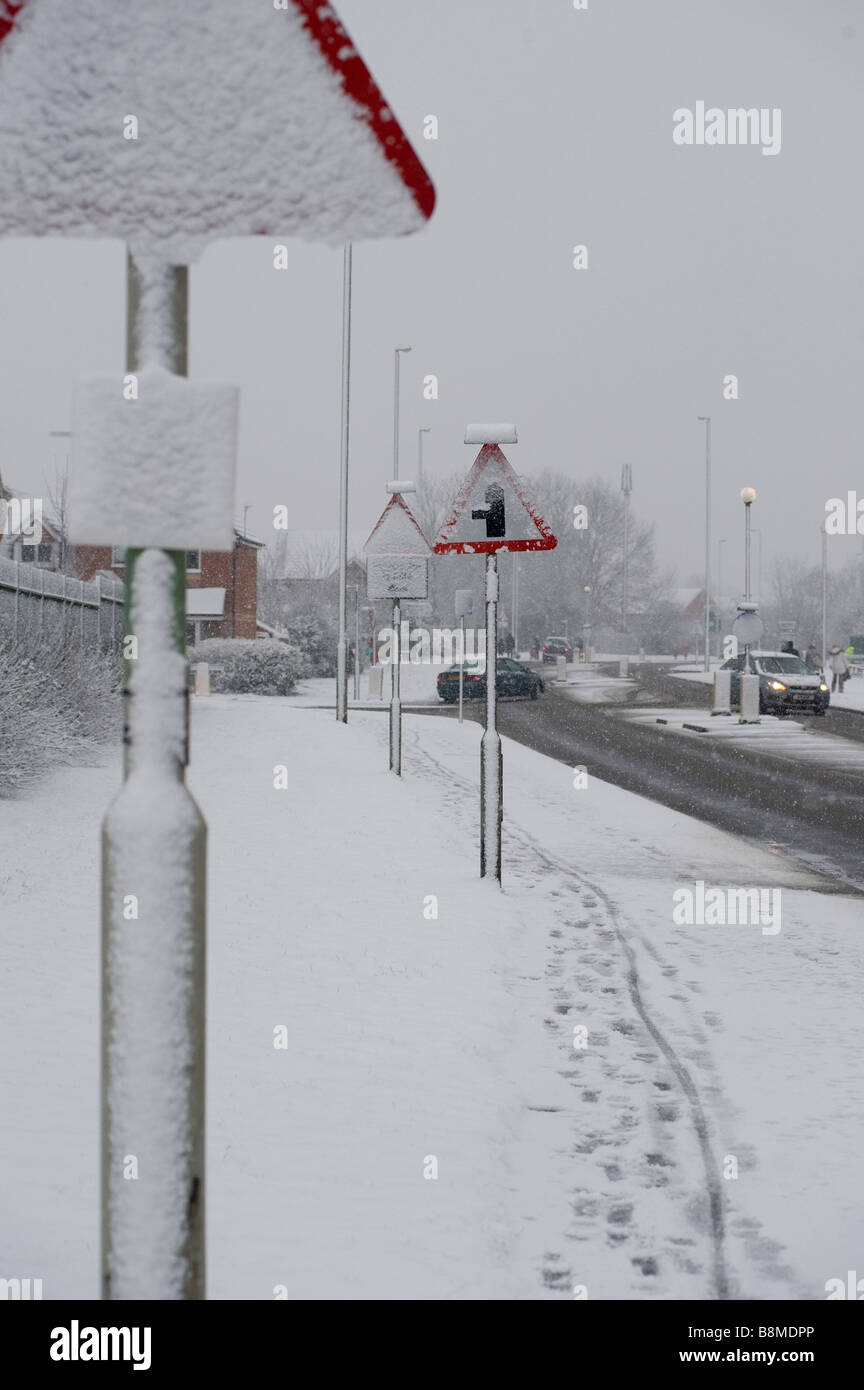 Leere schneebedeckte Fahrbahn mit Spuren im Schnee auf einer Straße im Winter in England Stockfoto