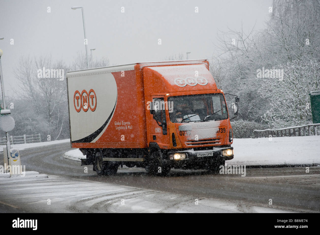 Fahren einen TNT Lieferung LKW durch Schnee und Eis an einem Wintertag in England zu Lieferungen Stockfoto