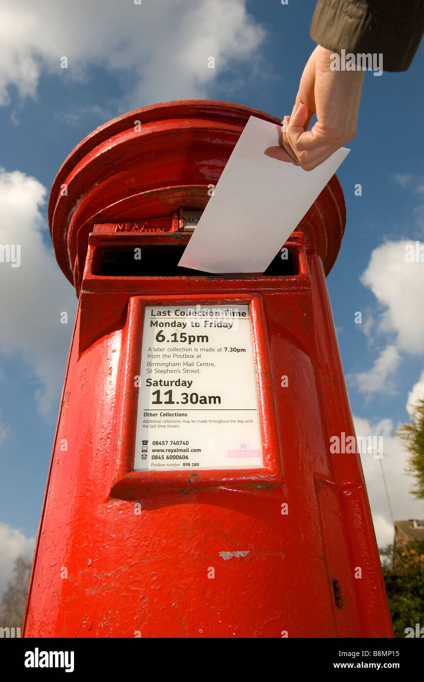 Ein Brief wird in ein helles rot Royal Mail Briefkasten in Worcestershire England gebucht. Stockfoto