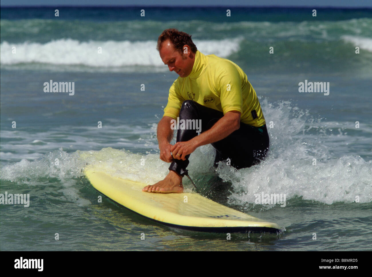 Polzeath Cornwall UK A Surflehrer wird gezeigt, wie sich das Board befestigen Stockfoto