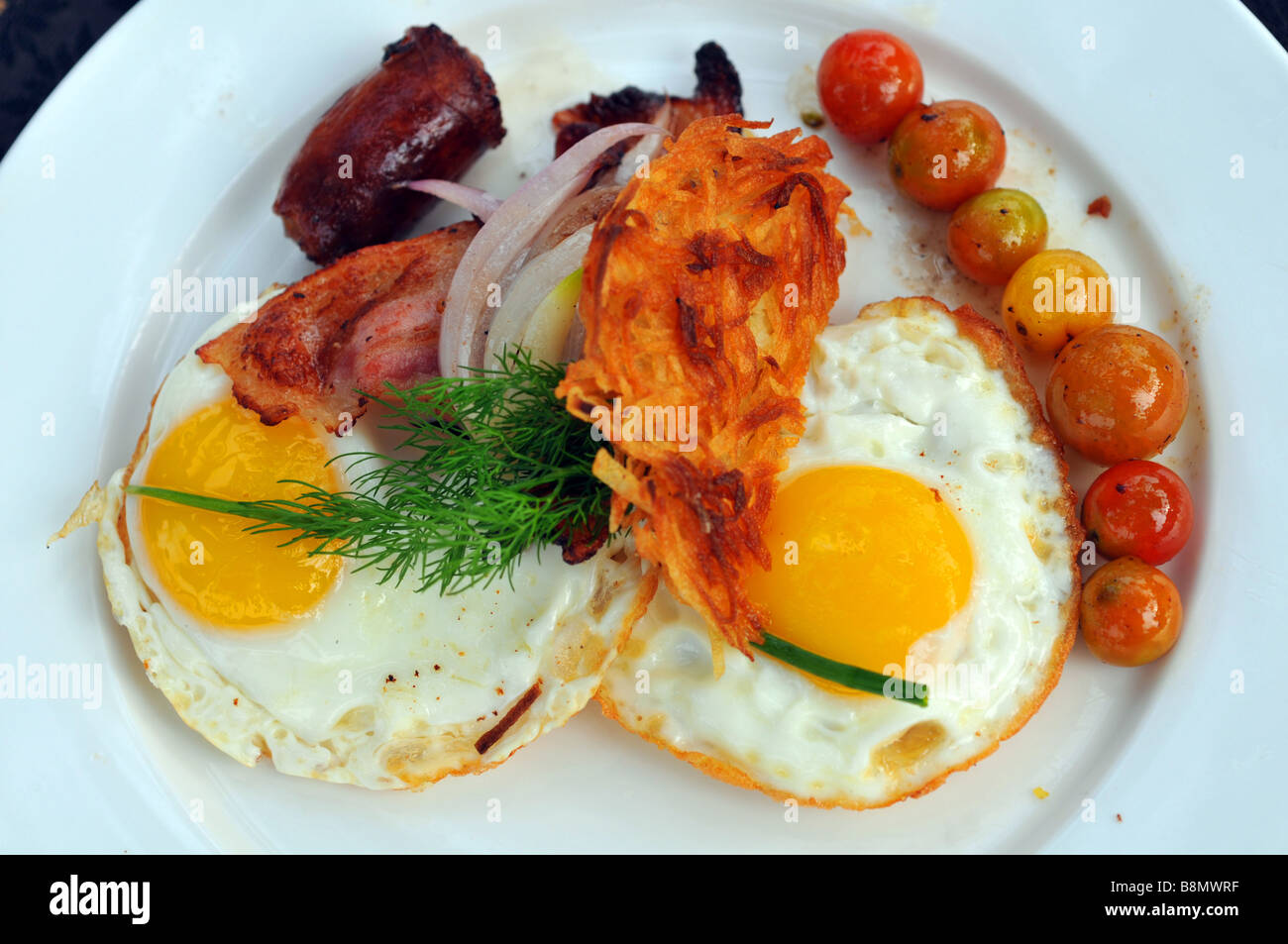 Frühstück, Teller mit Spiegelei, Speck, Würstchen und Tomaten Stockfoto
