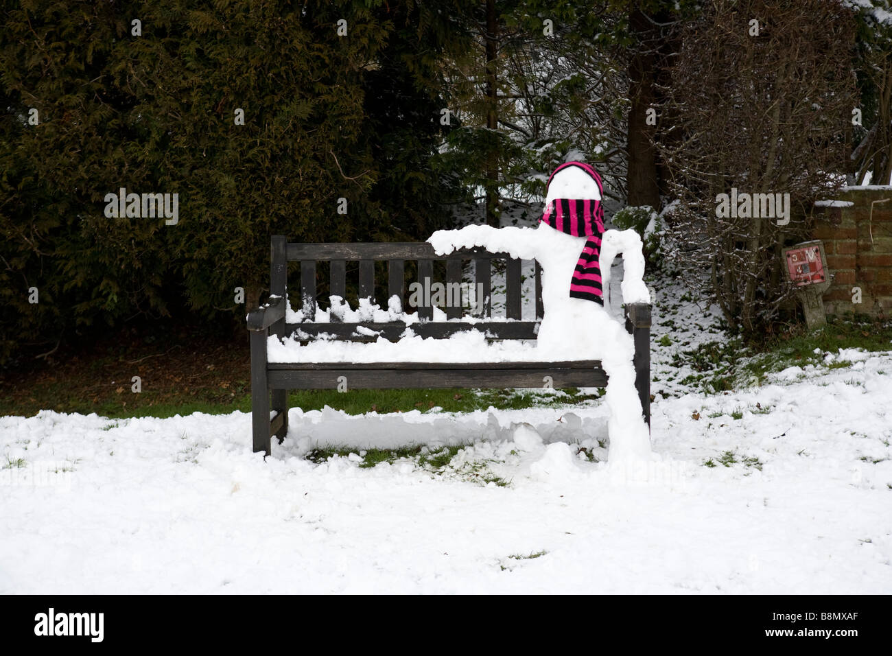Schneemann auf einer Bank sitzend Stockfoto