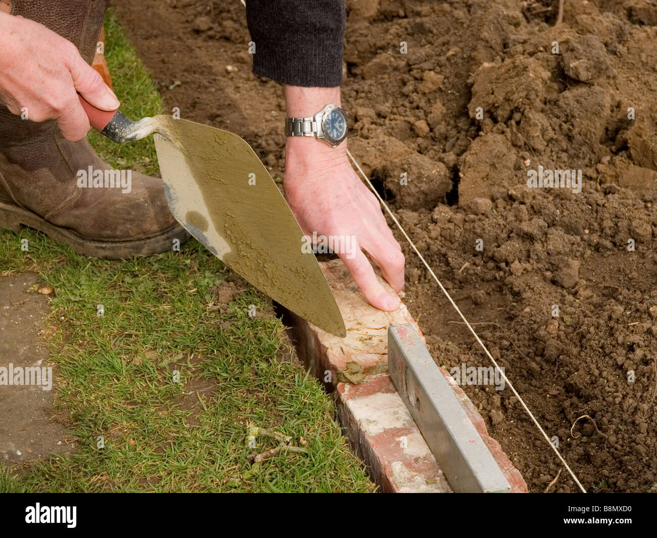 Verlegung einer Backstein Kante Garten Rasen Stockfoto