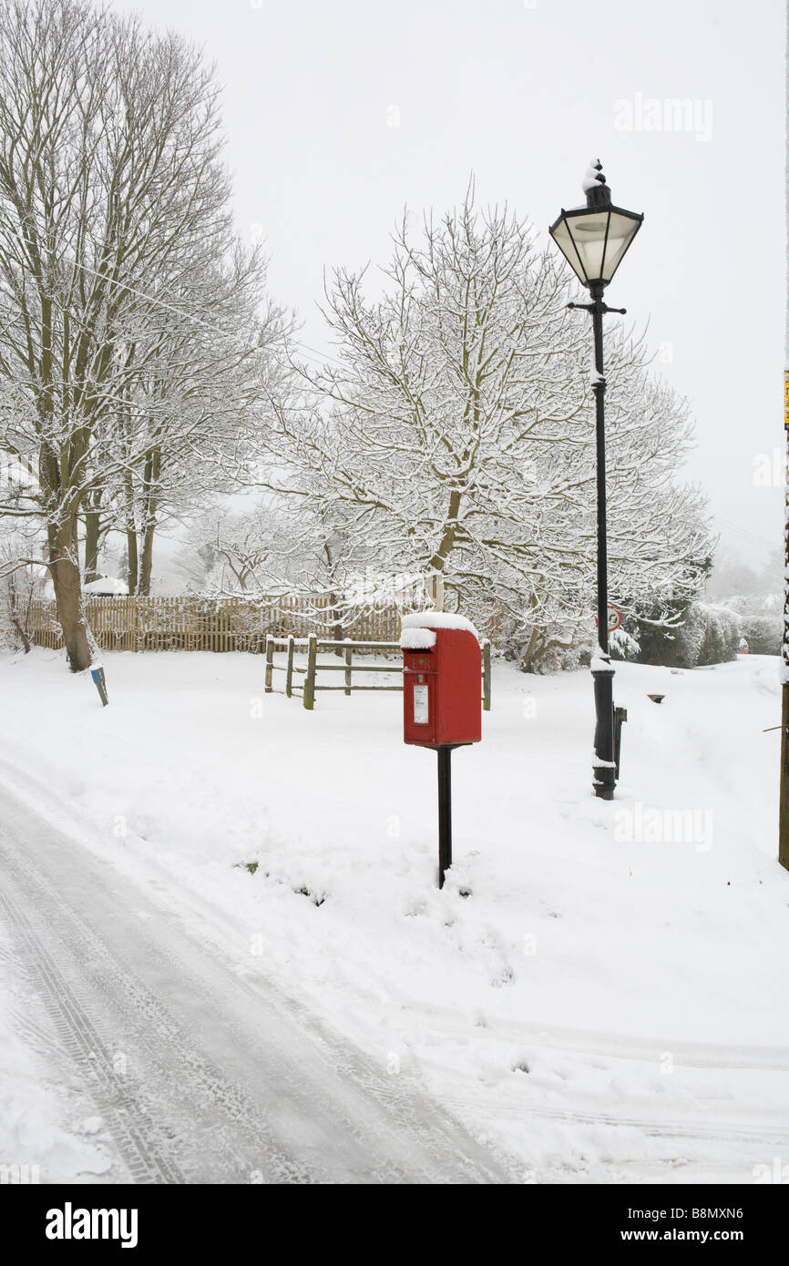 bildhafte Schnee-Szene von einem Dorf mit roten Briefkasten und Laternenpfahl Stockfoto