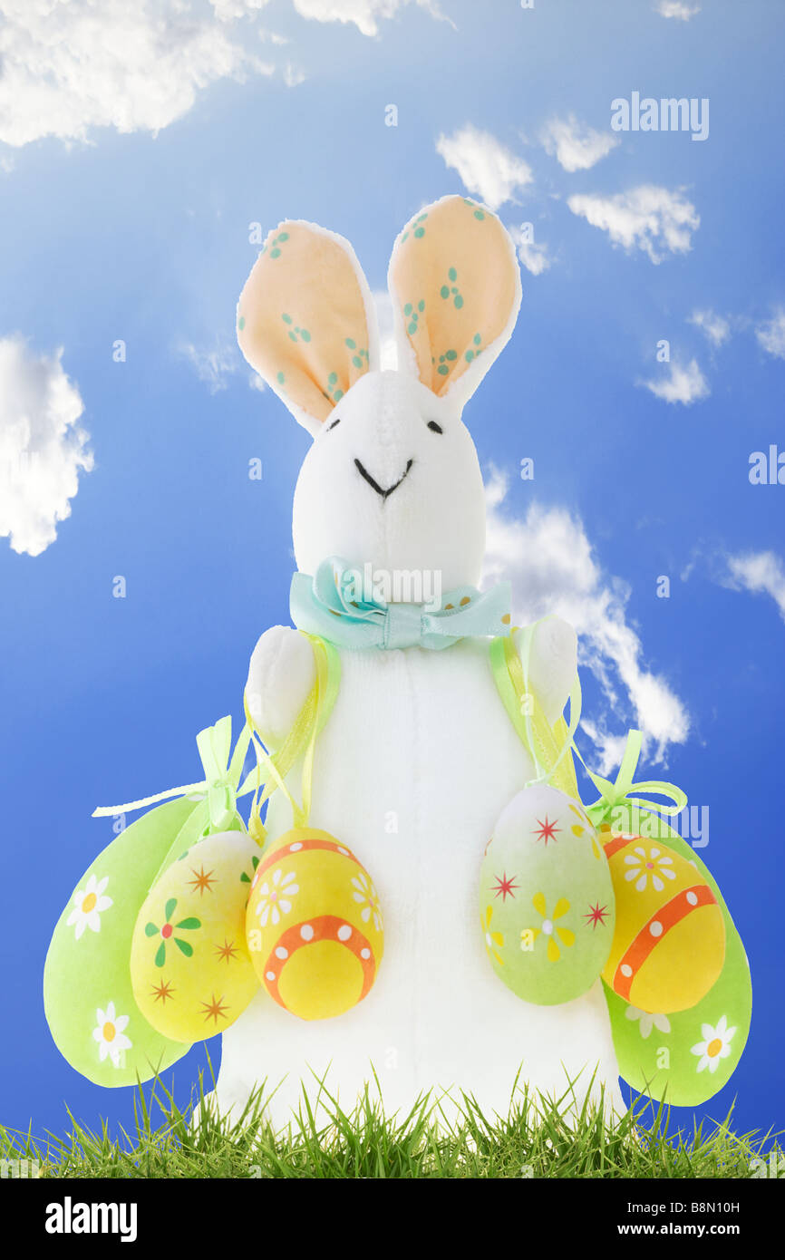 Osterhase mit dekorativen Eiern gegen klaren blauen Himmel als Hintergrund Stockfoto