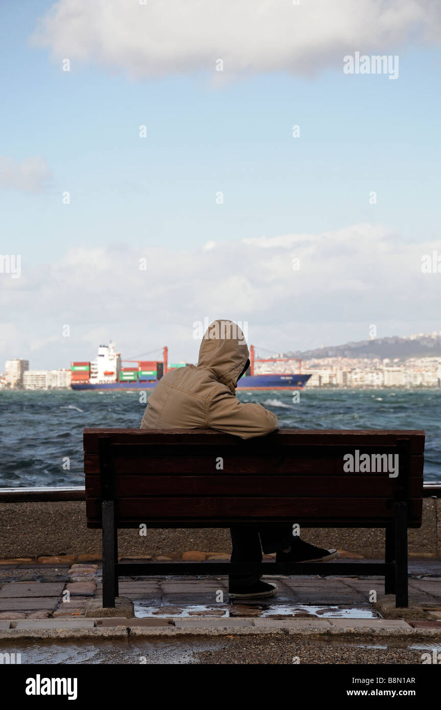 Mann sitzen sitzt auf seinem eigenen auf einer Bank Gesicht Aussehen suchen zugewandten Ägäische Meer Golf von Izmir Türkei gesehen von hinten Rückansicht Stockfoto