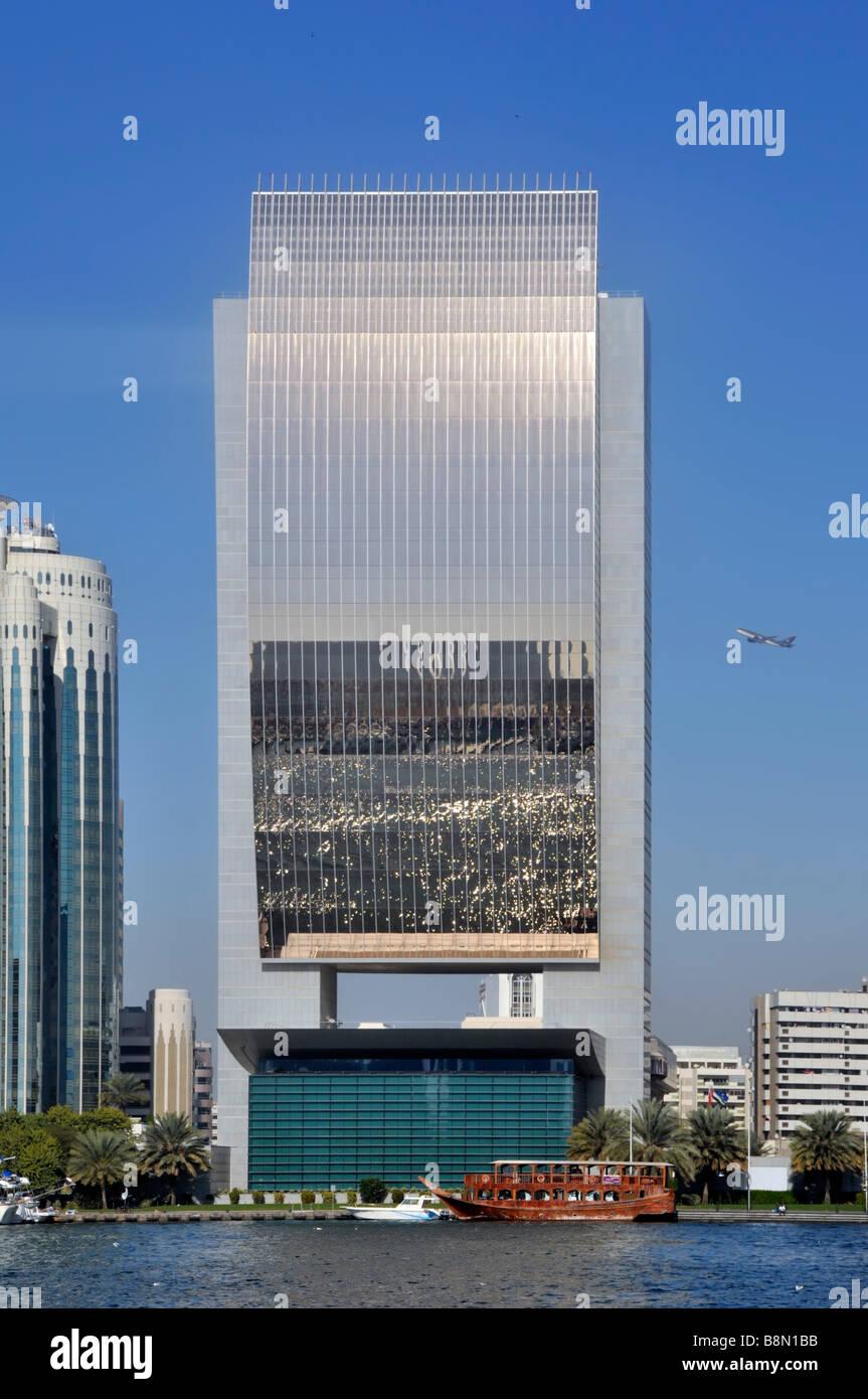 Dubai Creek und moderne Gebäude Architektur Skyline mit gebogener Front der Nationalen Bank in Dubai und Airliner, die VAE Naher Osten Asien Stockfoto