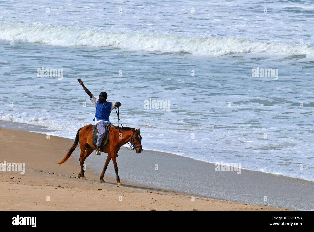 Mann auf Reiten Wellen für weibliche Touristen am Strand, The Gambia "West Afrika" Stockfoto