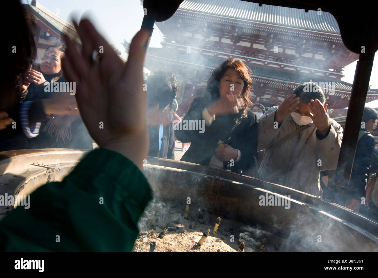 Besucher Senso-Ji Tempel Welle Weihrauch Rauch über sich selbst aus einer Urne zur Abwehr von schlechter Gesundheit und zu beheben und Krankheiten zu heilen. Stockfoto