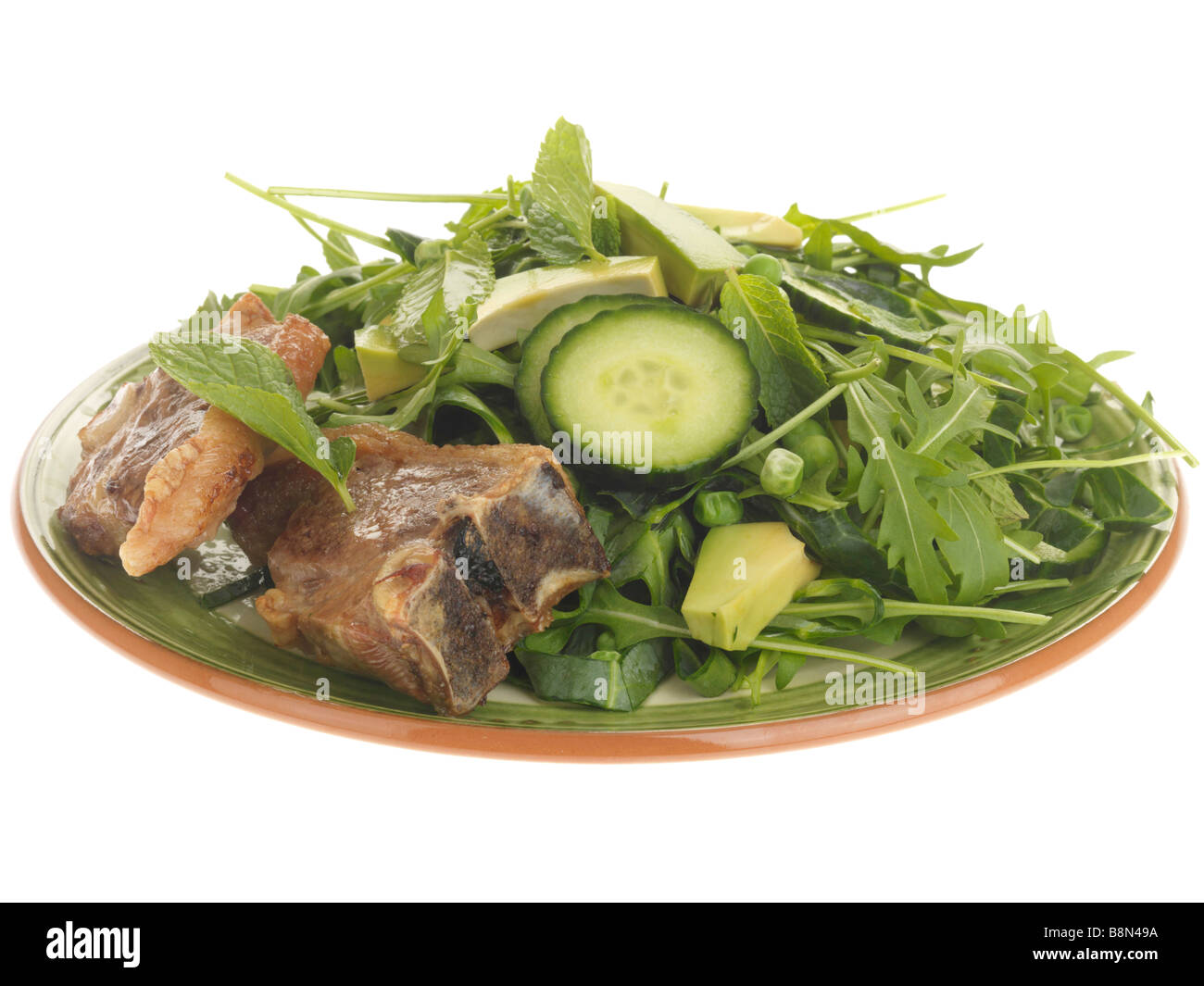 Ein frisch zubereitetes, zarte süße Lammkoteletts mit Avocado Salat und Rucola Blätter gegen einen weißen Hintergrund mit keine Menschen und einen Freistellungspfad isoliert Stockfoto