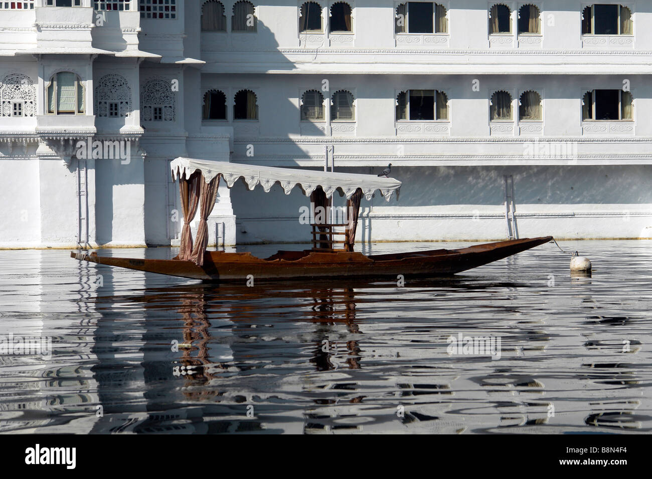 alte indische traditionelle Boot durch das Lake Palasthotel am Pichola-See mit Reflexionen Stockfoto