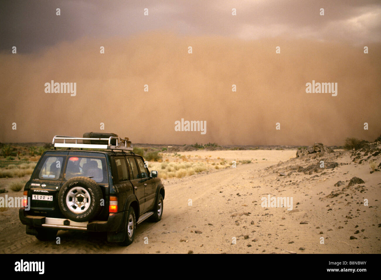Fahrzeug mit Annäherung an Sandsturm in der Wüste Stockfoto