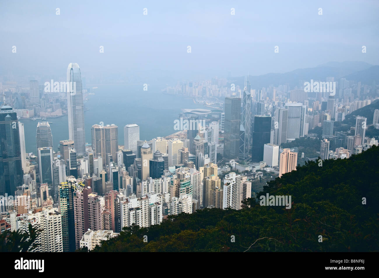 Bürotürme und Mehrfamilienhäuser von Hong Kong von The Peak mit Victoria Harbour & Kowloon durch Dunst sichtbar Stockfoto