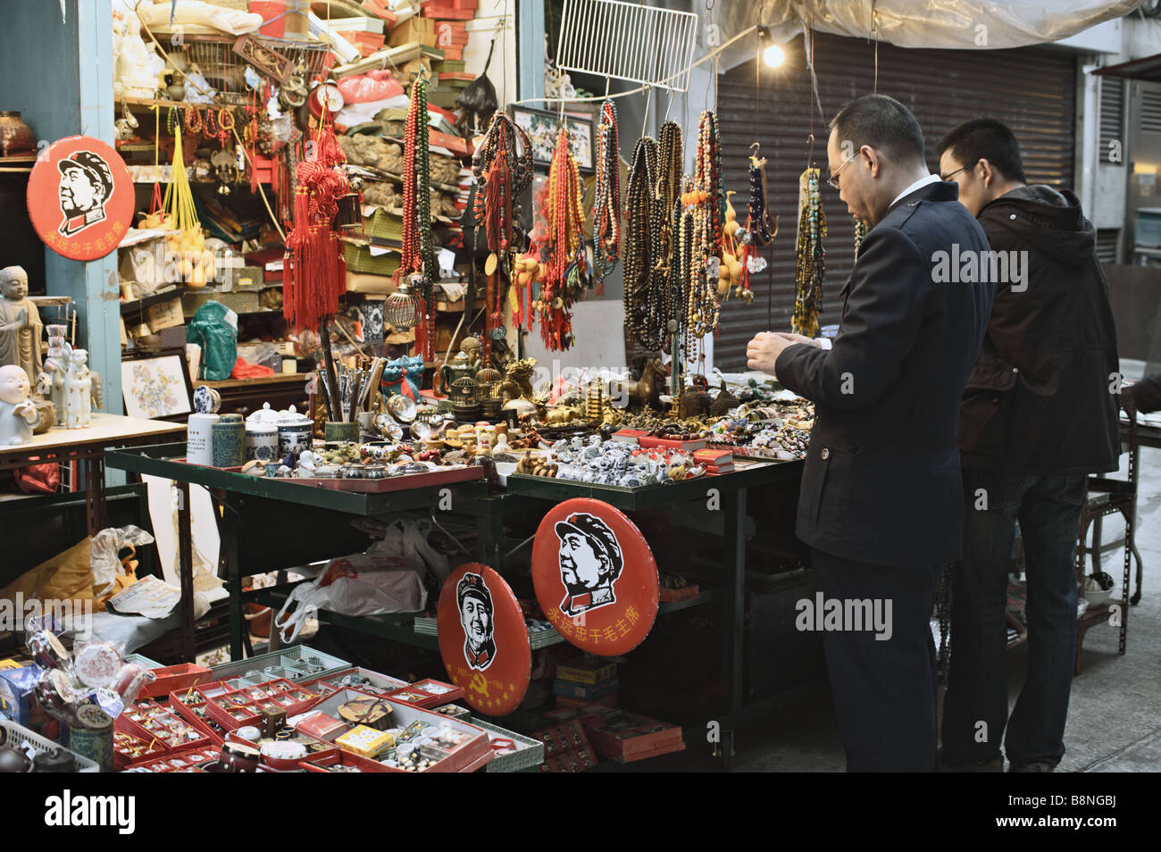 Käufer, die Vermessung von Mao Zedong Souvenirs zum Verkauf am Stall am oberen Lascar Zeile Hong Kong Stockfoto