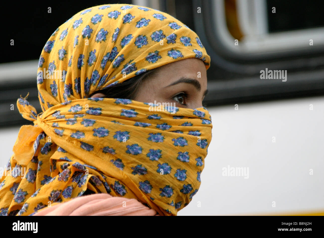 Junge indische Frau mit Schal über Mund und Kopf Stockfoto