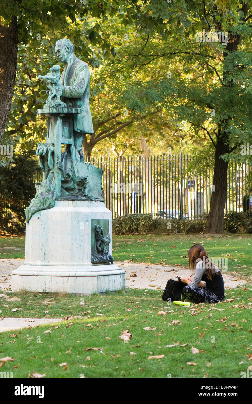 Frankreich, Paris, Weibchen sitzen auf dem Rasen in der Nähe von Statue im park Stockfoto