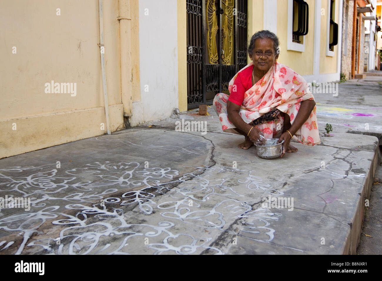Indien-Pondicherry Frau Bürgersteig vor der Tür mit traditionellen Reiswasser Neujahr Muster dekorieren Stockfoto