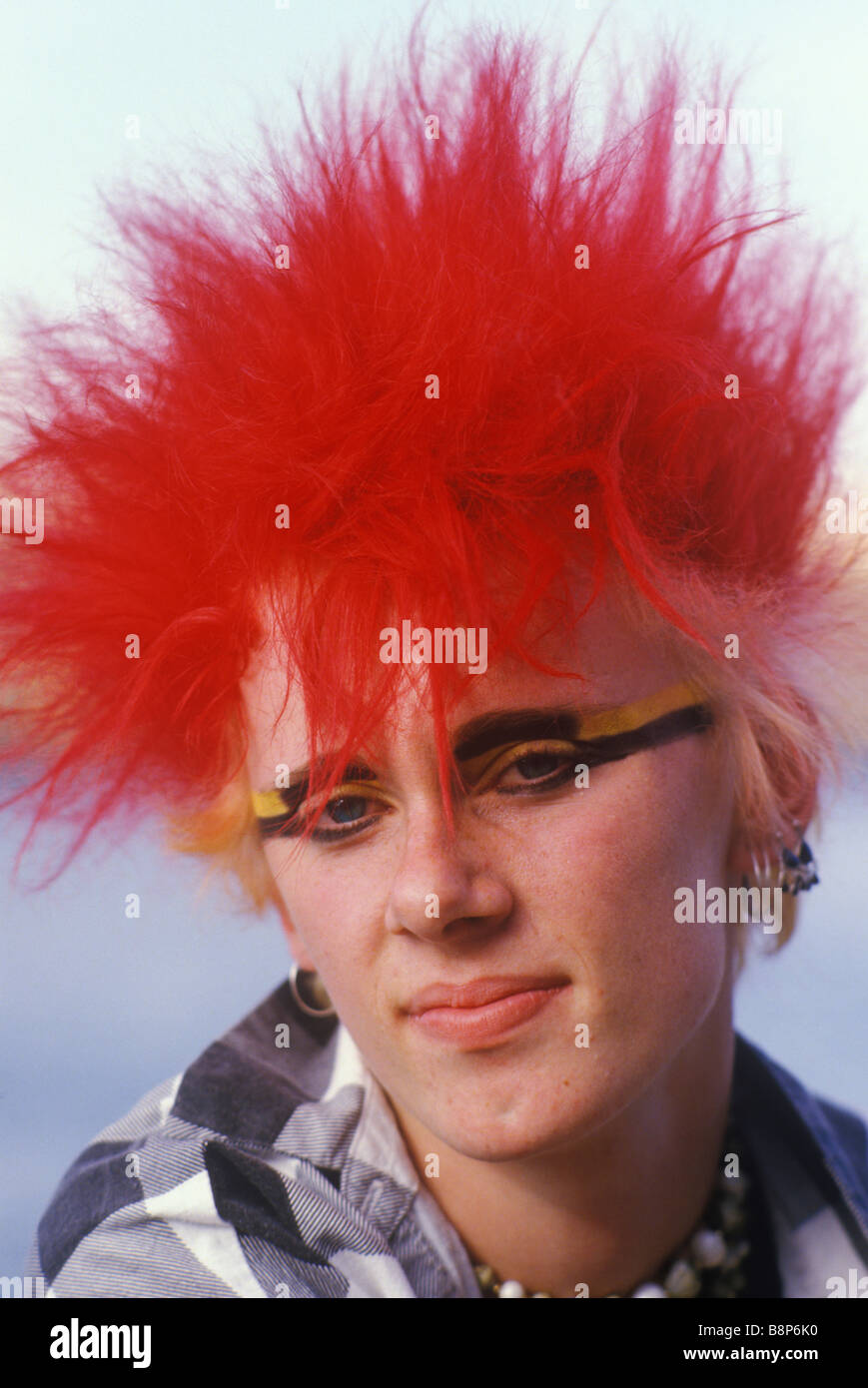 Punk der 1980er Jahre teenboy mit leuchtend roten Haaren und gelben und schwarzen Augen Make-up ca. 1985 London UK HOMER SYKES Stockfoto