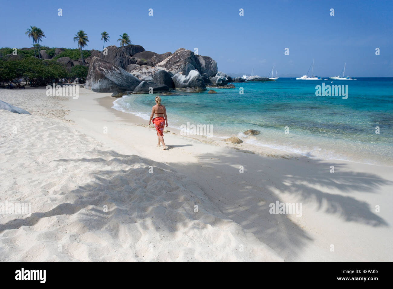 Eine Frau geht entlang des Strandes in der Nähe von großen Felsbrocken, die die Bäder in Virgin Gorda, BVI, West umfassen Stockfoto