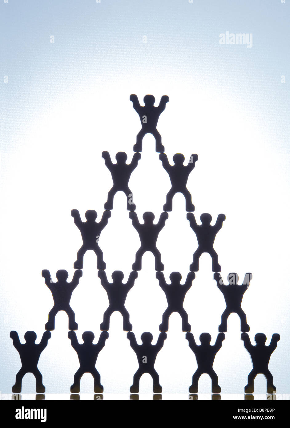 Modellfiguren bilden Pyramide vor blauem Hintergrund Stockfoto