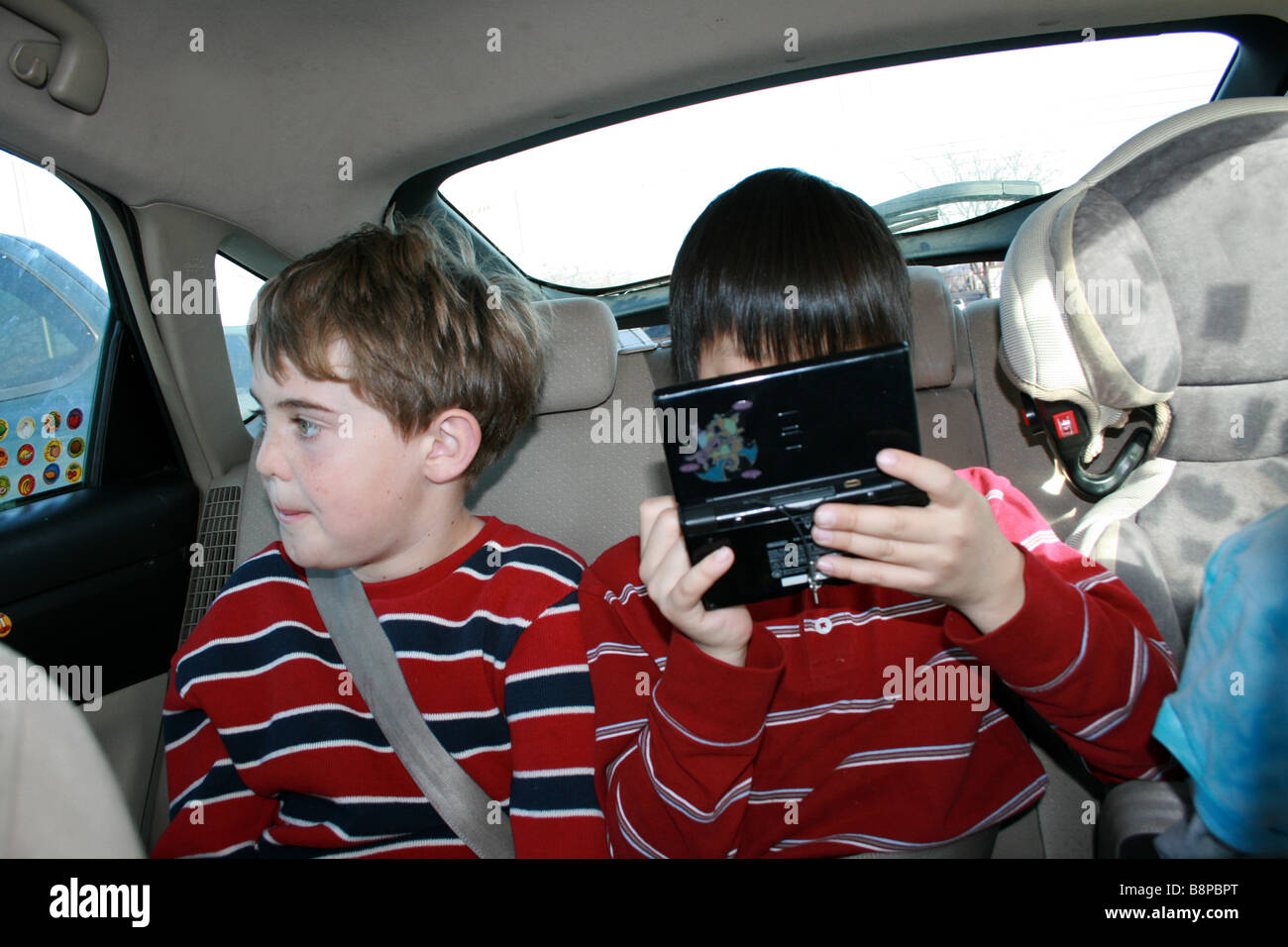 zwei jungen, die Fahrt in einem Auto ein Kind spielen elektronische Spiel, Nintendo ds Stockfoto
