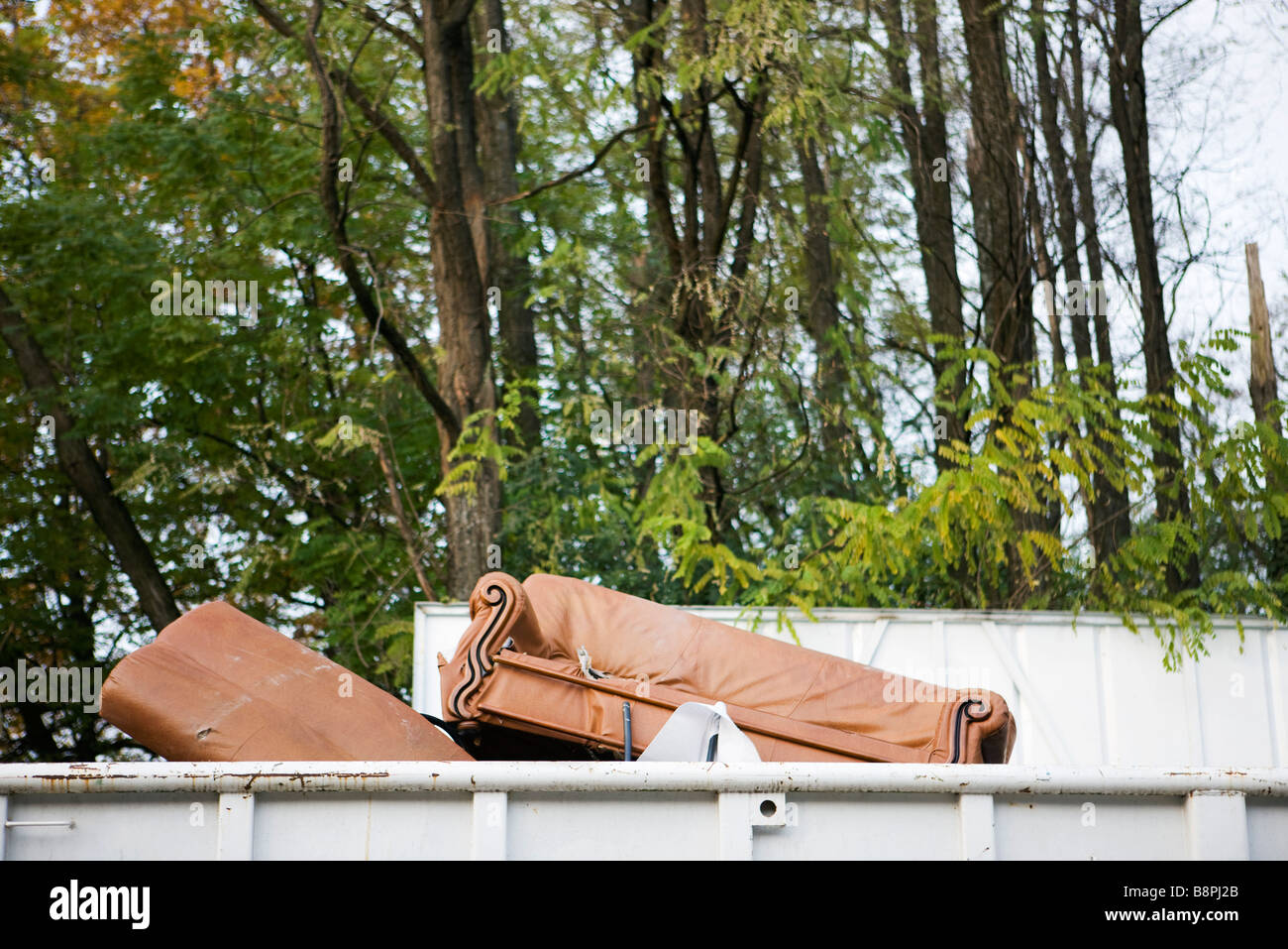 Sofa ragte aus Spitze der Müllcontainer Stockfoto