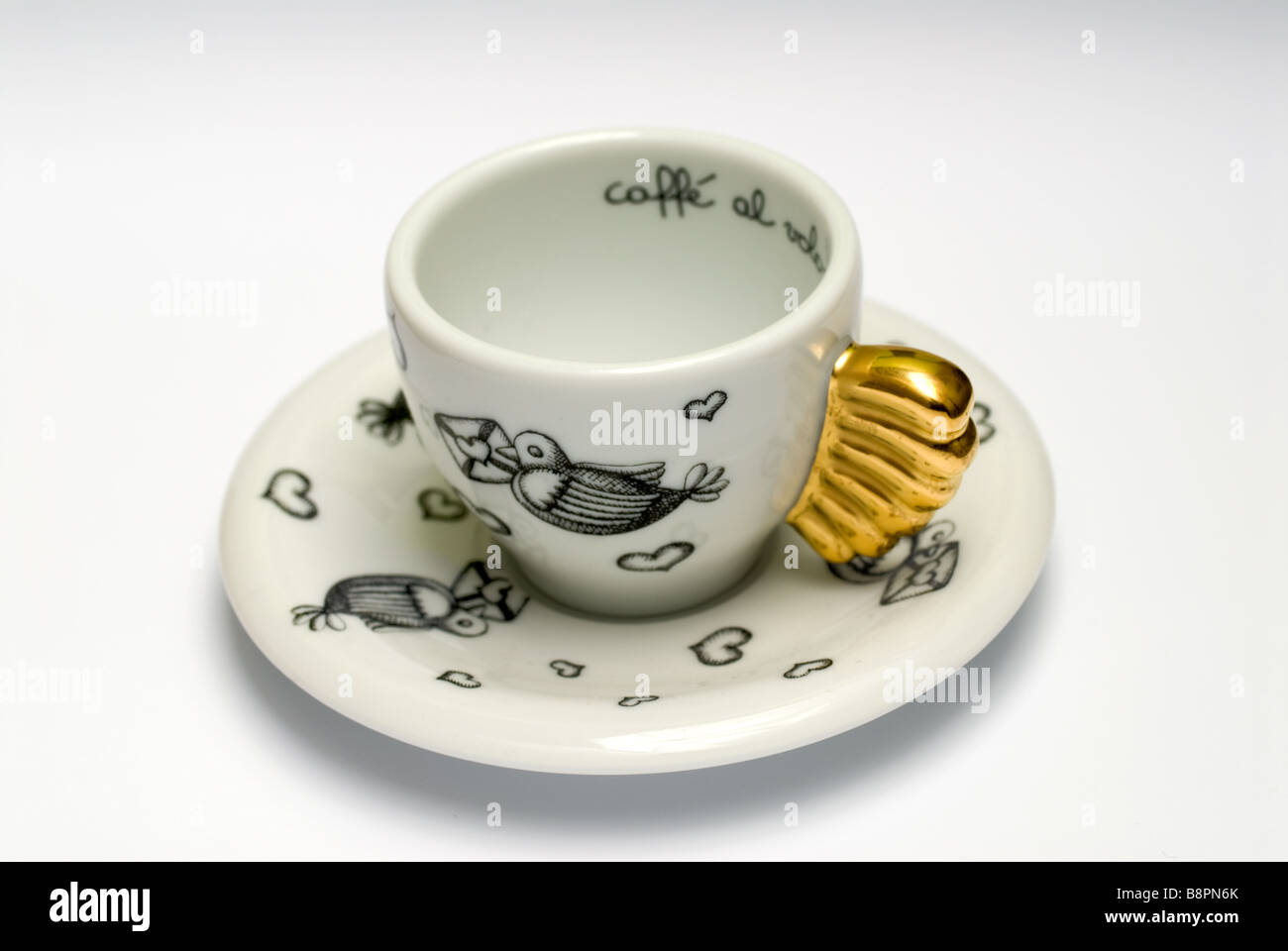 weiße Tasse und weiße Untertasse mit schwarzen Verzierungen und goldenen Griff Stockfoto