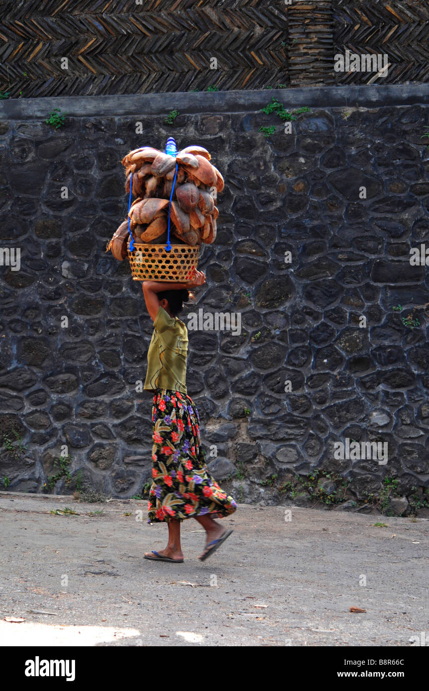 Bali Aga alte Dame Durchführung Zeug auf ihrem Kopf, Julah Dorf, Tejakula, Bali, Indonesien. Stockfoto