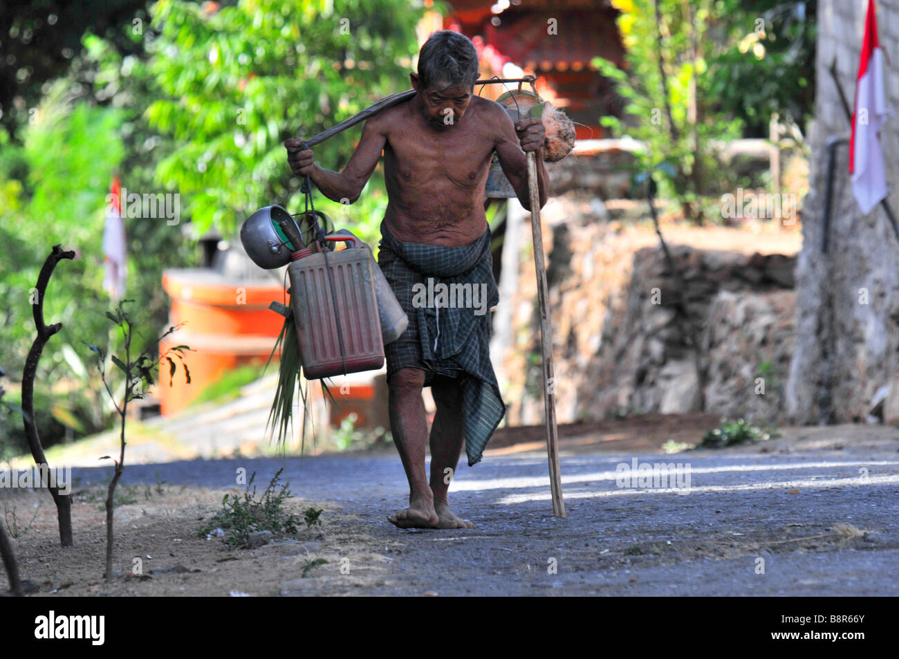 Bali Aga Greis tragenden Zeug auf seiner Schulter pole, Julah Dorf, Tejakula, Bali, Indonesien. Stockfoto