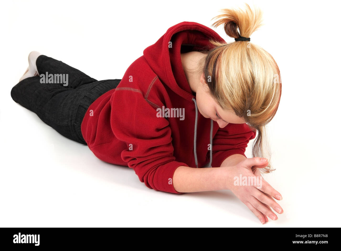 Porträt der jungen Frau in rotes Sweatshirt auf Boden liegend, Studio gedreht Stockfoto