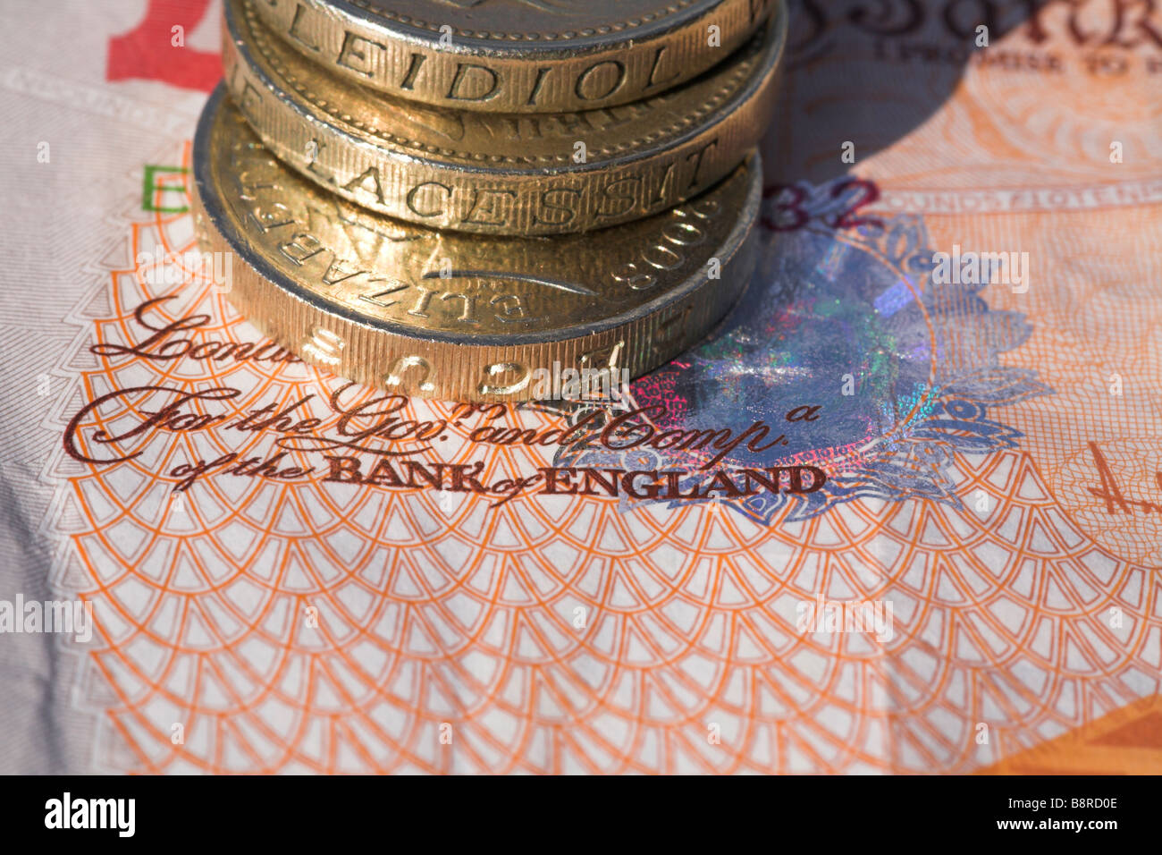 Bank von England Banknoten mit Haufen von Pfund-Münzen. Stockfoto