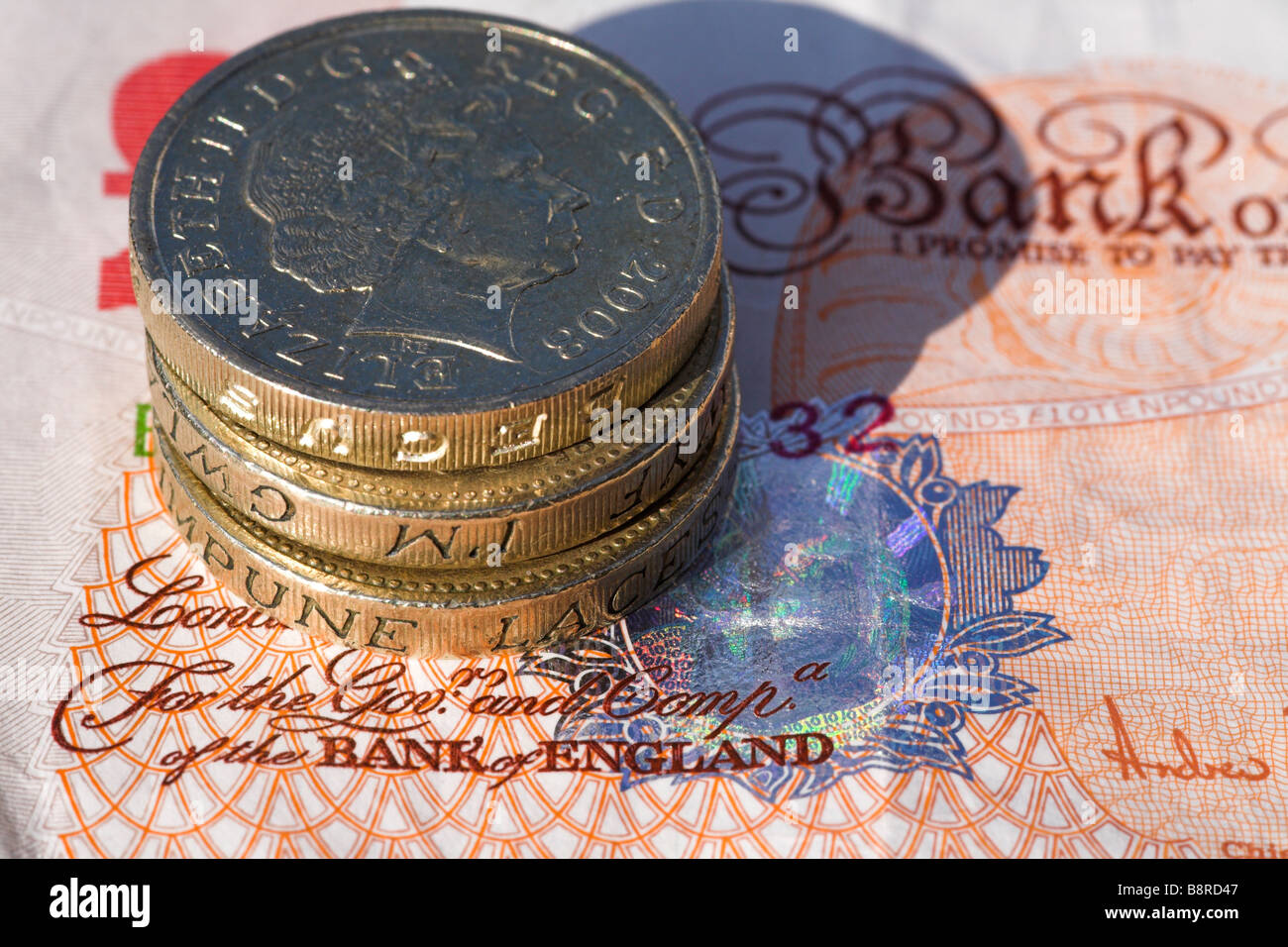 Bank von England Banknoten mit Haufen von Pfund-Münzen. Stockfoto