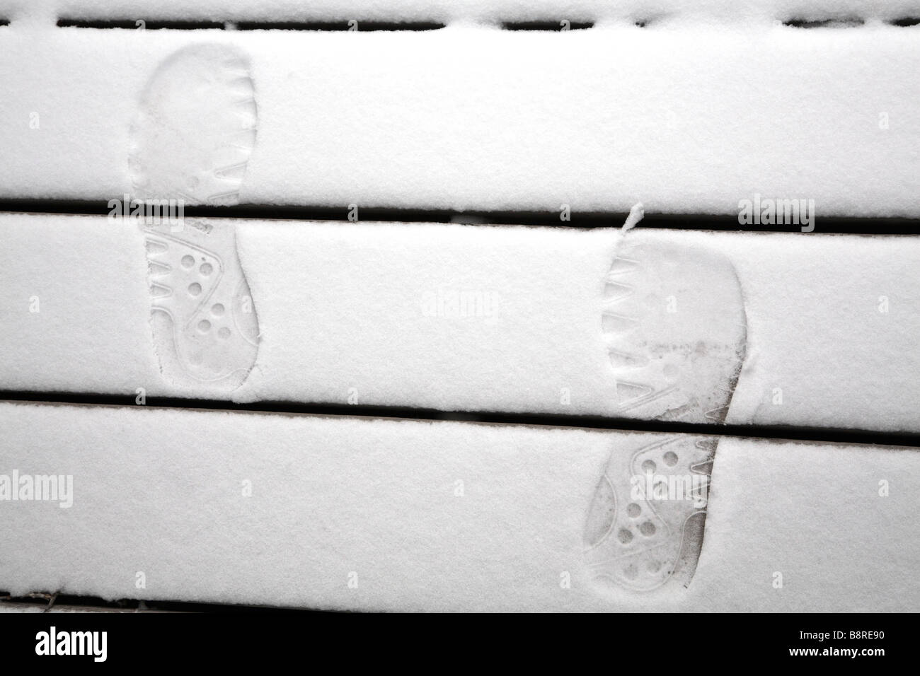 Fußspuren im Schnee auf Holzstufen. Stockfoto