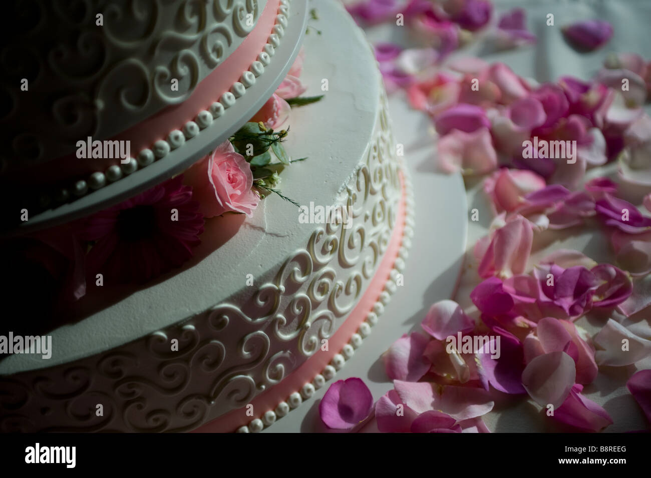 Rosenblätter verstreut eine Multi Tier Hochzeitstorte Stockfoto