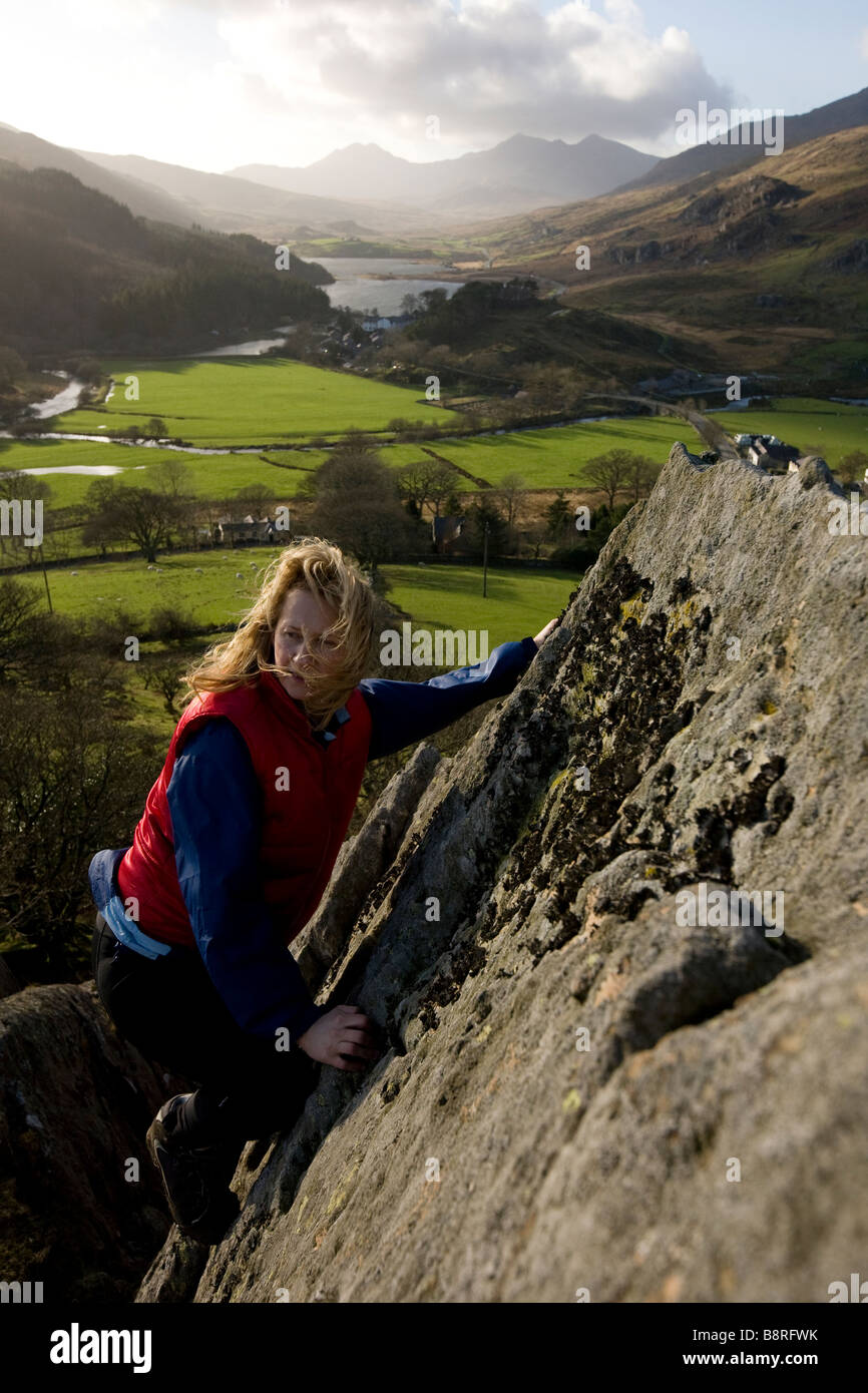 Weibliche Bergsteiger auf Felswand mit Llyn Mymbyr und Snowdon Hufeisen in der Ferne Snowdonia Gwynedd North Wales UK Stockfoto