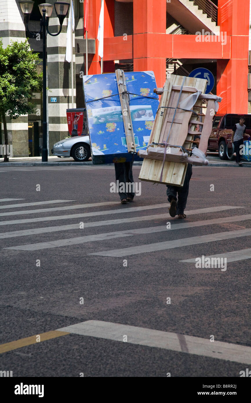 Bangbang Träger überqueren einer Straße in Chongqing. Wegen der steilen Hügel können Fahrräder verwendet werden. Stockfoto