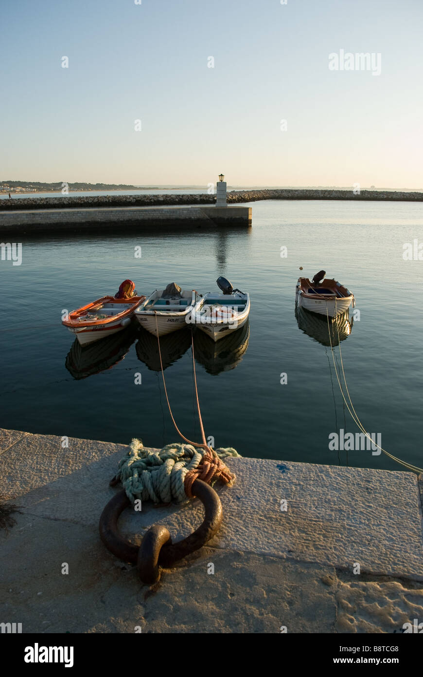 Vier Boote sind an der steinernen Hafenmauer in Lagos, Algarve, Portugal gebunden. Stockfoto