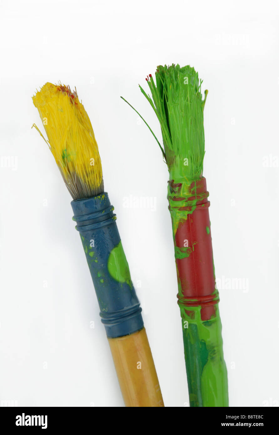 zwei schmutzige Pinsel bedeckt in den Farben gelb und grün zur Veranschaulichung der ein abgeschlossener Auftrag oder Aufgabe mit großer Stockfoto