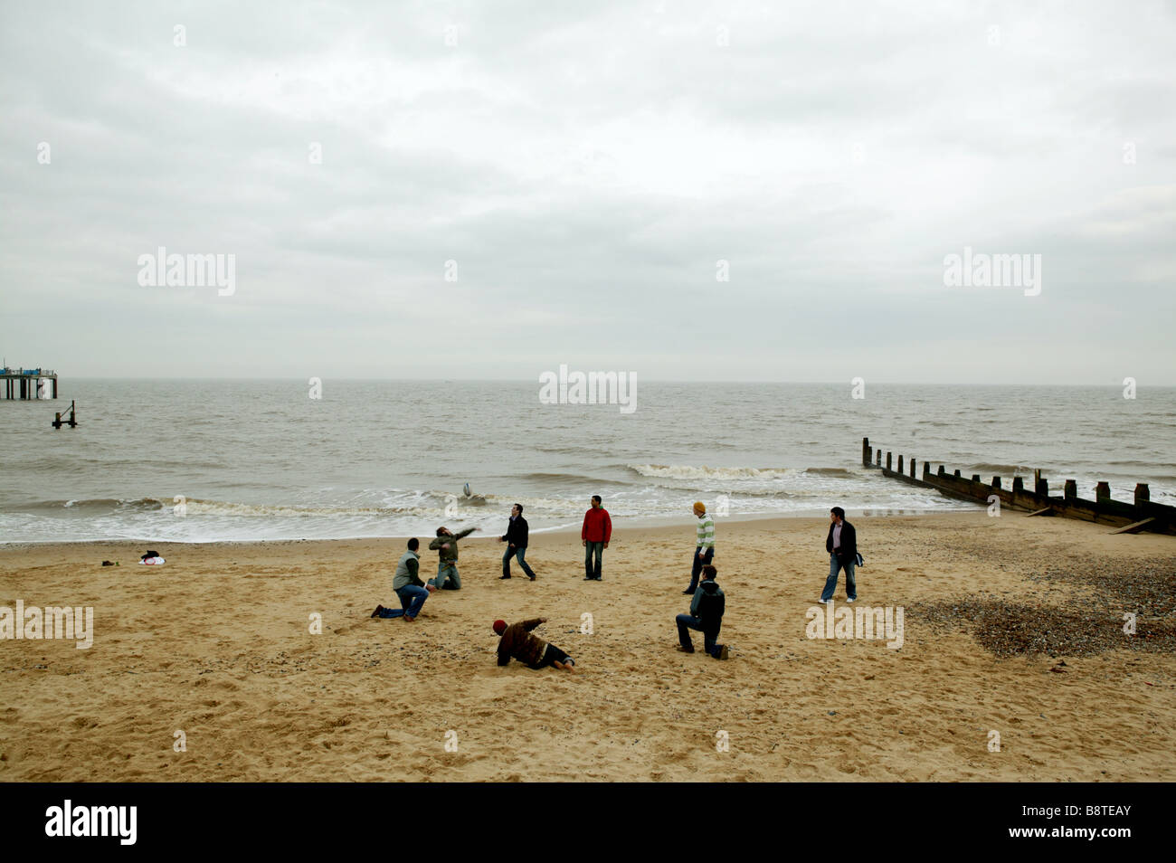 Gruppe junger Männer spielen Ball auf einem Sandstrand im englischen winter Stockfoto