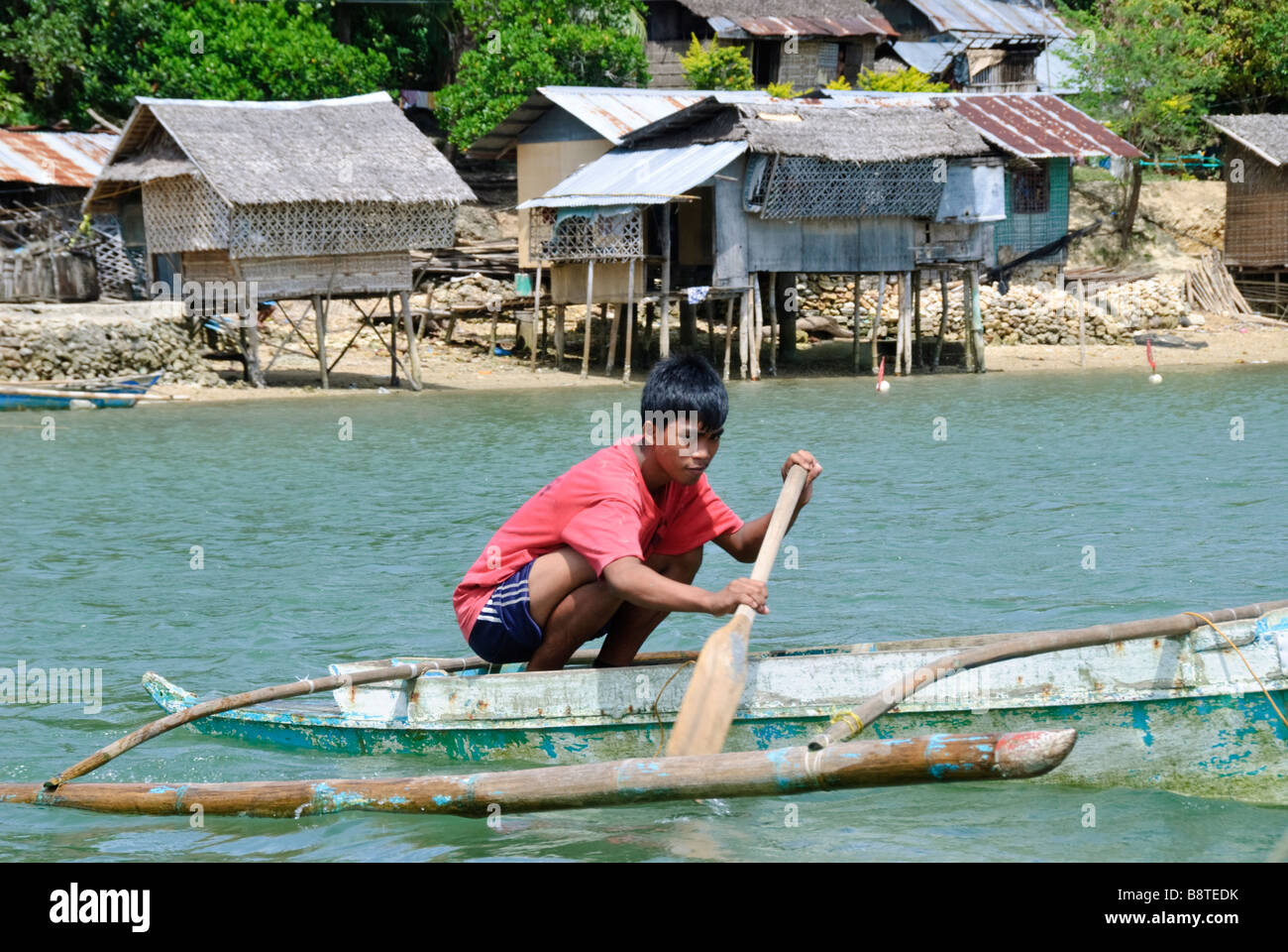 Junge paddeln Bangka (Ausleger-Kanu) in den Gewässern um Guimaras, Philippinen Stockfoto